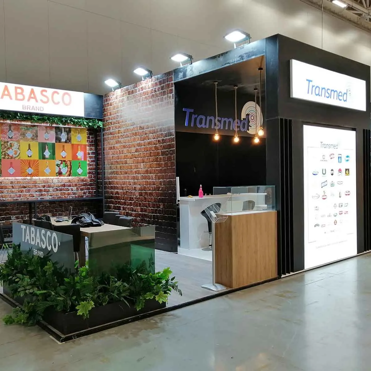 Transmed fuar standı, tuğla desenli duvar ve ışıklı logo kutuları
